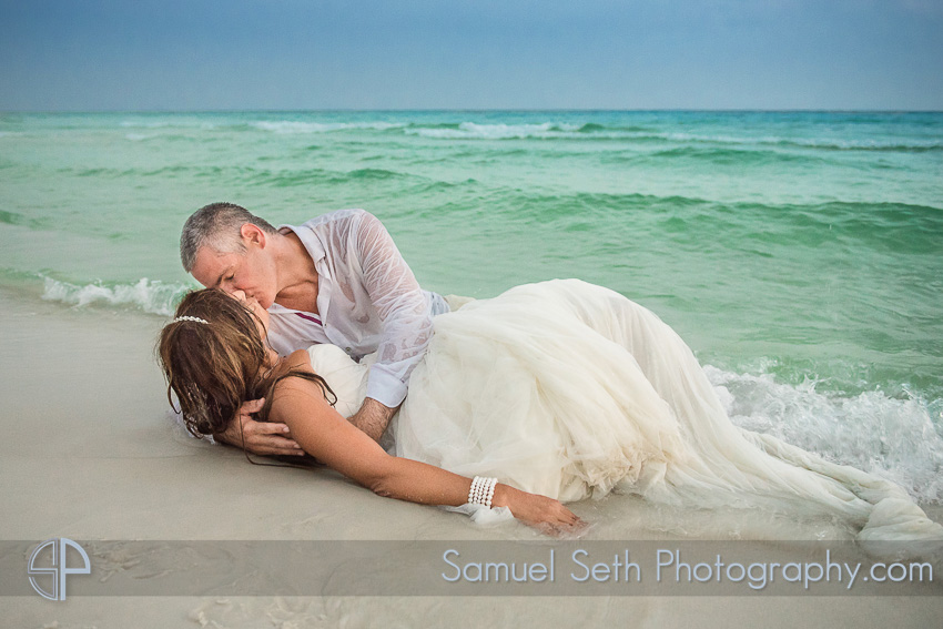 Bride and groom kissing on beach in water